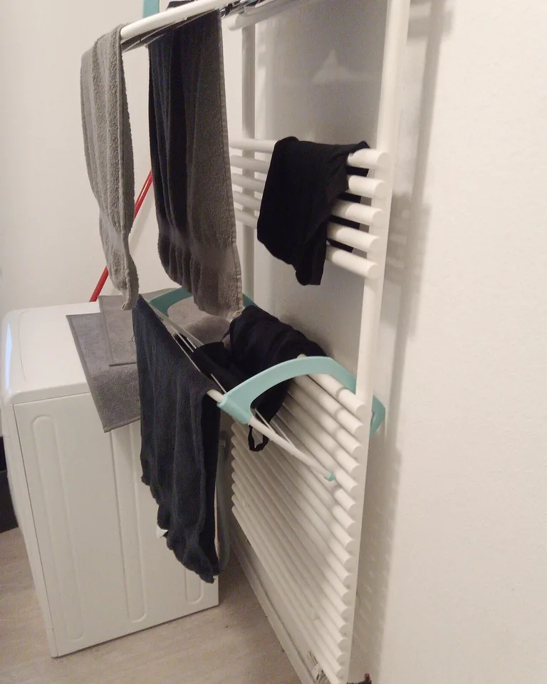 12 Stacked Laundry Room Ideas for Small Spaces That Make Every Inch Count 8 Wall-mounted drying rod with shirts on hangers in a laundry room