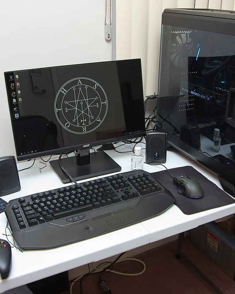 Tidy gaming setup with aligned monitor, keyboard, and a single warm accent light in a bedr