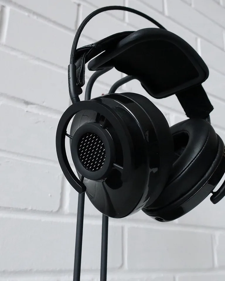 Headphones hanging on an under-desk hook next to a controller